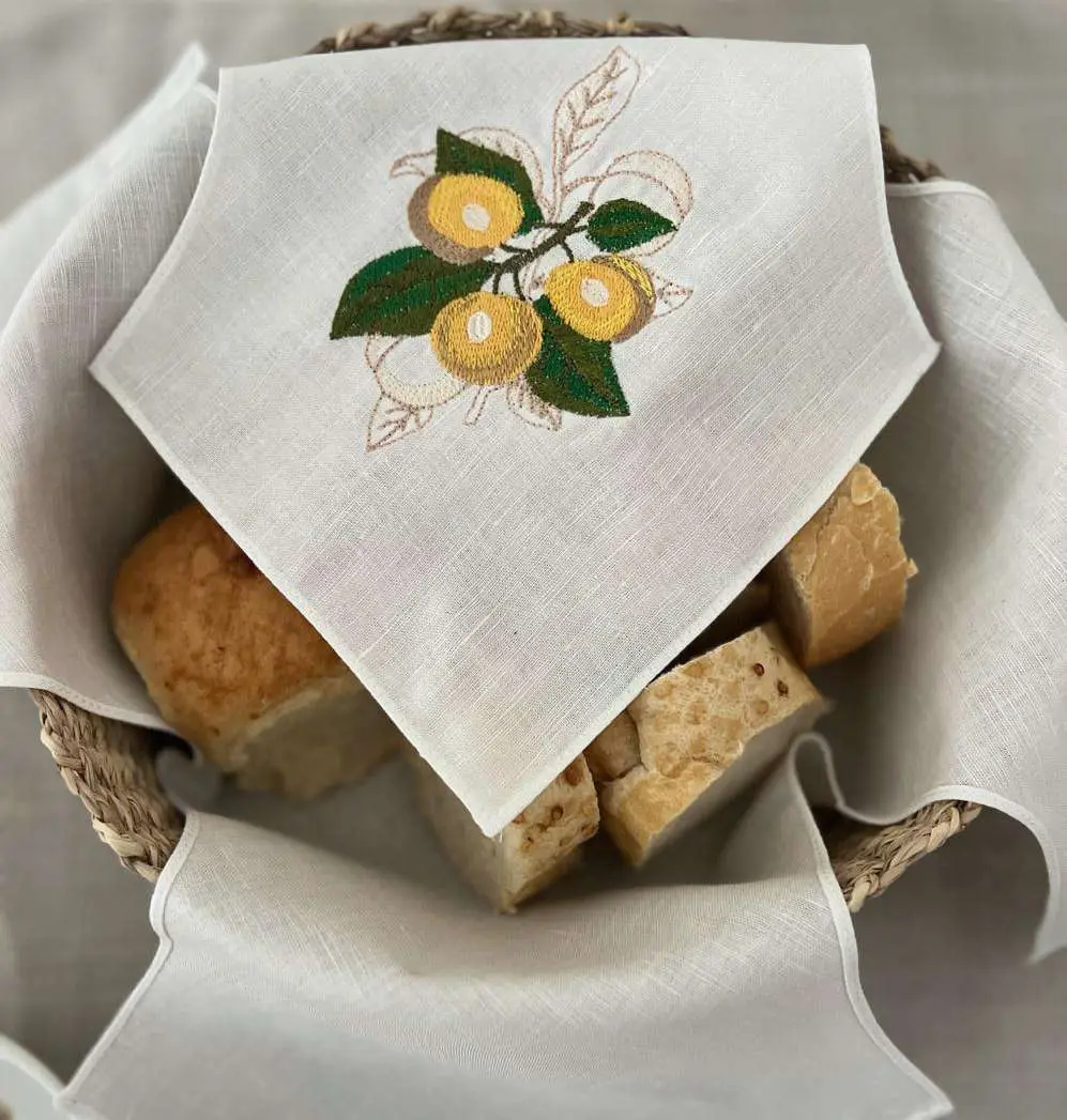 Panera de lino con limones bordados sobre una canasta de pan